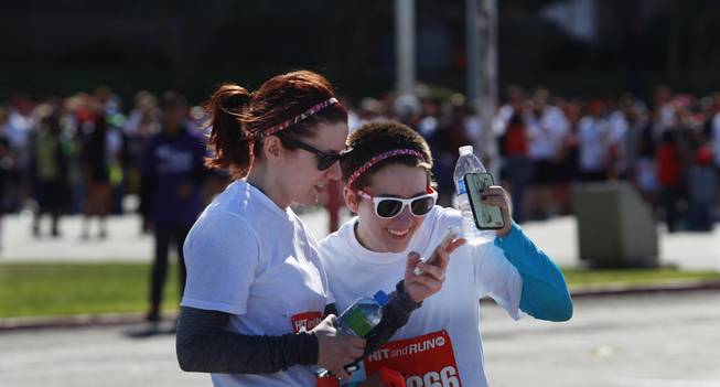 Torri Lippacher, left, and Ria Farmer look at video they shot of themselves participating in the Hit and Run 5k Saturday, March 1, 2014 at Sam Boyd Stadium. The Hit and Run 5k, a fun run with various obstacles to navigate, is being held or planned in two dozen cities across the country.